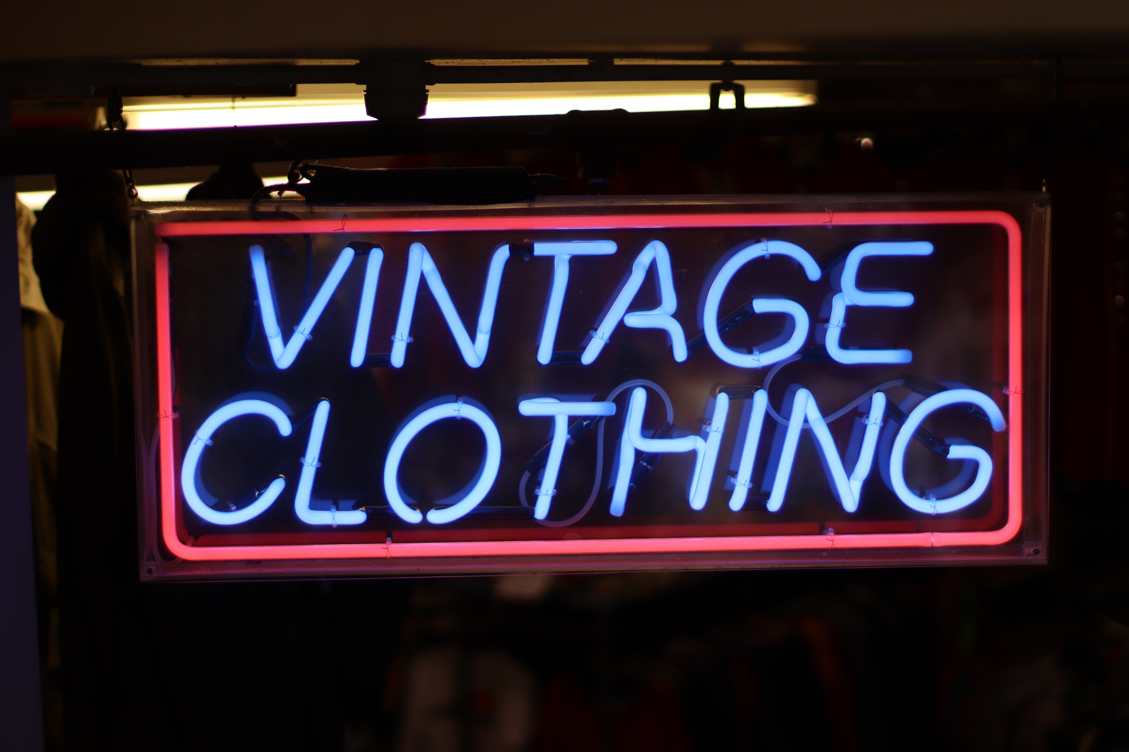 Neon sign reading 'Vintage Clothing' at AJ Vintage, a curated thrift store specializing in rare 90s sportswear, retro streetwear, and classic band tees.